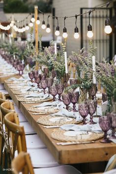 a long table is set with purple wine glasses and lavender flowers for an elegant dinner