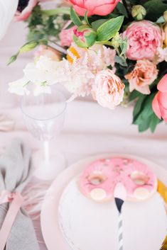 the table is set with pink and white desserts, silverware, and flowers