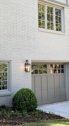 a white brick house with two garage doors and one light on the side of it