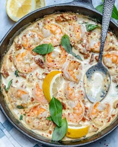 a skillet filled with shrimp and lemons on top of a blue table cloth