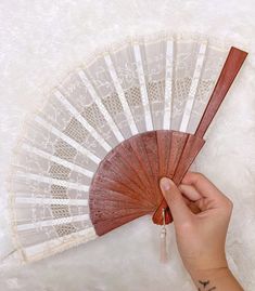 a hand holding a red fan on top of a white rug