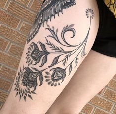 a woman's legs with tattoos on them and flowers in the middle of her leg