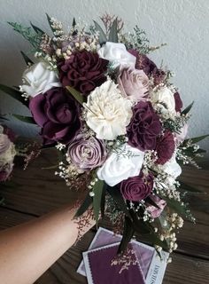 a bouquet of flowers sitting on top of a table next to a person's hand