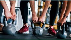 several people holding kettles in a row with their feet on the barbells