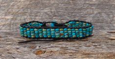 Measures: 9" Can be adjusted down to about 7" Width: 5/8" Weight: 10 grams Want a unique accessory to brighten your day? This Turquoise bracelet is handcrafted with delicate beadwork that has been strung together with leather into an array of blue shades to create a design that will be sure to flatter the wrist. This is an item that will certainly be cherished and appreciated by anyone who treasures handcrafted jewelry! Adjustable Turquoise Wrap Bracelet For Festival, Handmade Turquoise Leather Bracelet Spiritual, Adjustable Turquoise Hand-strung Wrap Bracelet, Adjustable Turquoise Hand-strung Beaded Bracelets, Adjustable Hand-strung Turquoise Beaded Bracelets, Unique Adjustable Turquoise Beaded Bracelet, Artisan Blue Adjustable Wrap Bracelet, Adjustable Turquoise Beaded Artisan Bracelets, Adjustable Leather Bracelet With Round Beads