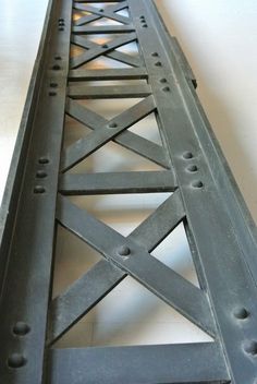 an old metal bridge with holes in the bottom and one section missing, on a white surface