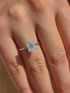 a woman's hand with a diamond ring on top of her finger and an engagement band