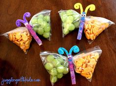 four bags filled with fruit and butterflies on top of a wooden table next to an apple