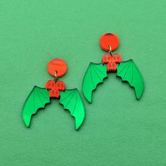 Holly shaped earrings with green leaves shaped like bat wings and red berries shaped like ghosts. They have gold-toned jump rings and red circular stud posts. Holly Earrings, Red Ghost, Mirror Acrylic, Bat Wing, Holiday Jewelry, Christmas Holly, Bat Wings, Fish Hook, Gold Tone Metal