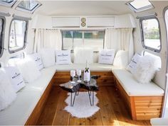 a living area with white couches and pillows on the floor in front of windows