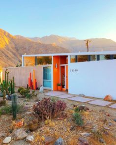 an orange and white house in the desert with mountains in the background