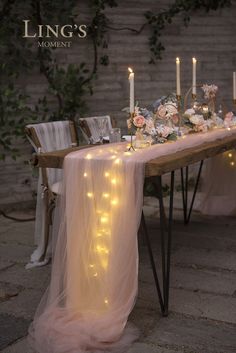 a long table with candles and flowers on it is set up for an outdoor dinner