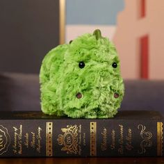 a green stuffed animal sitting on top of a book