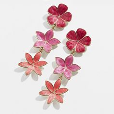 two pairs of pink and red flower earrings on a white surface with one pair dangling from the back