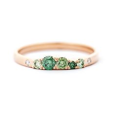 a gold band with green and white stones on the side, set in 18k rose gold