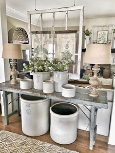 several white buckets sitting on top of a wooden table next to a mirror and lamp