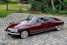 a red convertible car parked on top of a brick road