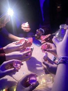 several people sitting at a table with their cell phones in front of them and one person holding a lighter