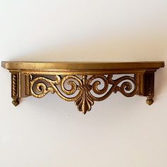 an ornate gold shelf on a white wall