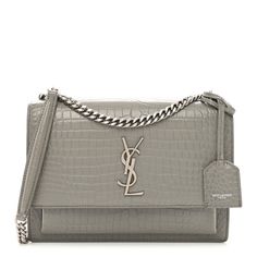 This is an authentic SAINT LAURENT Calfskin Crocodile Embossed Medium Monogram Sunset in Fog. This stylish shoulder bag is crafted of crocodile embossedcalfskin leather in gray. The bag features a polished silver chain shoulder strap with a leather shoulder pad, a front facing flap with a signature silver YSL logo, and an exterior pocket. This opens to a gray suede partitioned interior with a patch pocket. Quilted Toys, Denim Quilt, Ysl Logo, Velvet Quilt, Stylish Shoulder Bag, Saint Laurent Bag, Gray Suede, Emboss, Shoulder Pads