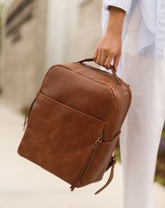 The go-anywhere bag, our La Jolie is the perfect backpack for the on-the-go parent, gym goer, jetsetter and more. With a capacity you wouldn't imagine, this bag can truly carry you through the day. Featuring limitless interior and exterior pockets for space as well as our finest luxe leather, look no further for the perfect bag. Our Luxe leather is more reactive to the touch and will feel lived-in over time. Hand selected because of its vintage feel and character, this full grain leather breaks Leather Diaper Bag Backpack, Leather Diaper Bag, Beautiful Backpacks, Stroller Hooks, Work Backpack, Backpack Free, Leather Product, Vegan Leather Bag, Diaper Bag Backpack