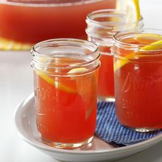 three mason jars filled with watermelon and lemon sit on a plate next to another jar