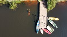 three canoes are docked at the end of a dock with a person standing on it