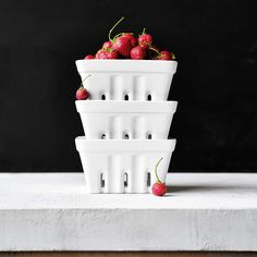 a stack of white bowls with strawberries in them on top of a countertop