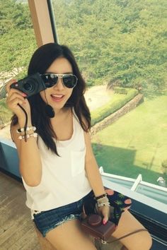 a woman sitting on top of a window sill holding a camera