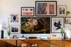 there are many framed pictures on the wall in this living room, including flowers and vases