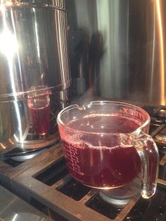 a pitcher of liquid sitting on top of a stove next to a pot filled with liquid