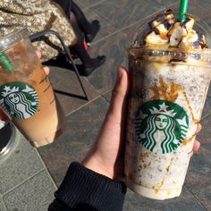 two starbucks drinks are being held by someone's hand