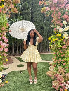 a woman in a yellow dress holding an umbrella over her head and posing for the camera