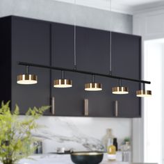 a kitchen with black cabinets and lights hanging from the ceiling