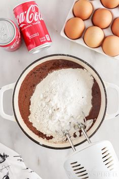 an overhead view of eggs and flour in a pan next to a can of coca - cola