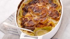 a casserole dish with potatoes and meat in it on a napkin next to a spoon