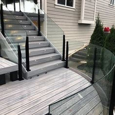 an outdoor deck with glass railing and stairs