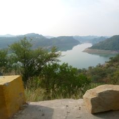 a bench sitting on top of a stone covered hillside next to a body of water