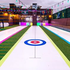 an indoor ice rink is decorated with lights and artificial grass for a party or event