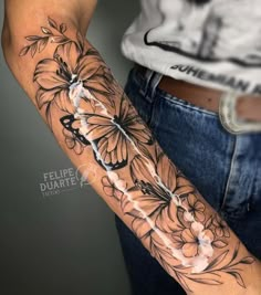 a woman's arm with flowers and butterflies on it, in black and white