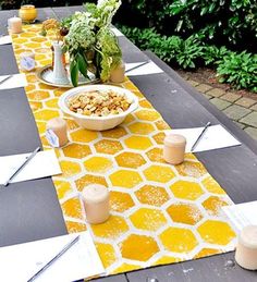 a long table with yellow and white patterned runneres on it, topped with bowls of food