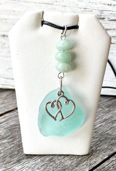 a necklace with two hearts on it and green glass beads hanging from the clasps