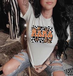 a woman sitting on top of a chair wearing a shirt with the word mom written in leopard print