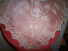 the back of a woman's dress with white embroidered flowers on red fabric and lace