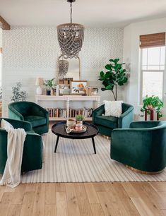 a living room filled with green furniture and a chandelier hanging from the ceiling