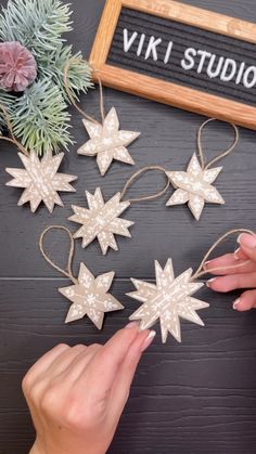 two hands are decorating wooden stars with twine