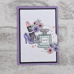 a card with an image of a shoe and perfume bottle on it, sitting against a wall