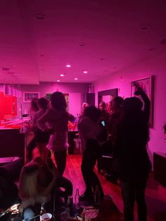 a group of people standing in a room with pink lighting on the walls and floor