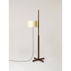 a wooden floor lamp with a white shade on the base and a black cord attached to it