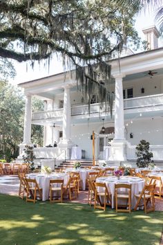 tables and chairs are set up in front of a large white house